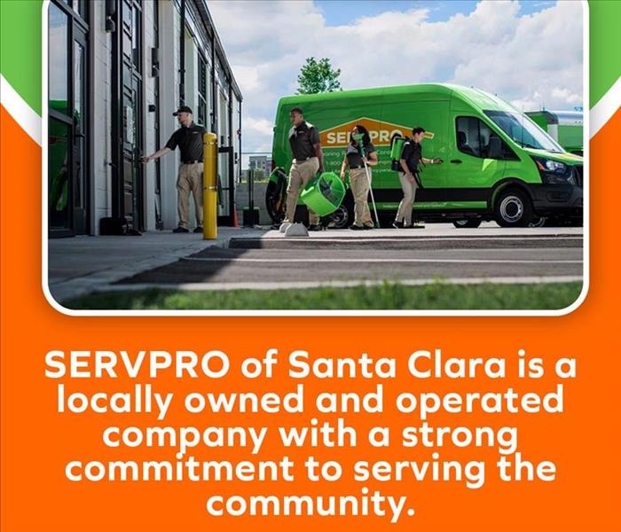 SERVPRO of Santa Clara team members in uniform unloading equipment from a green SERVPRO van outside a building.